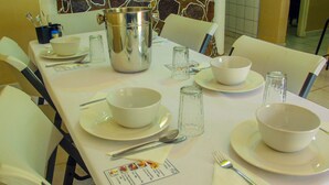 A dining table set with white plates, bowls, cutlery, and a menu. - BJ&T Vacation Homes (Kasane)