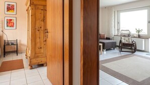 Un salon moderne avec un meuble en bois, un canapé, un fauteuil à bascule et une grande fenêtre.