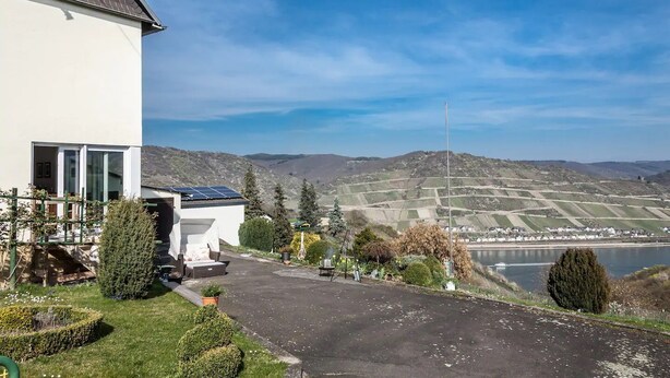 Un bâtiment moderne doté de panneaux solaires, offrant une vue sur une vallée et donnant sur un plan d’eau.
