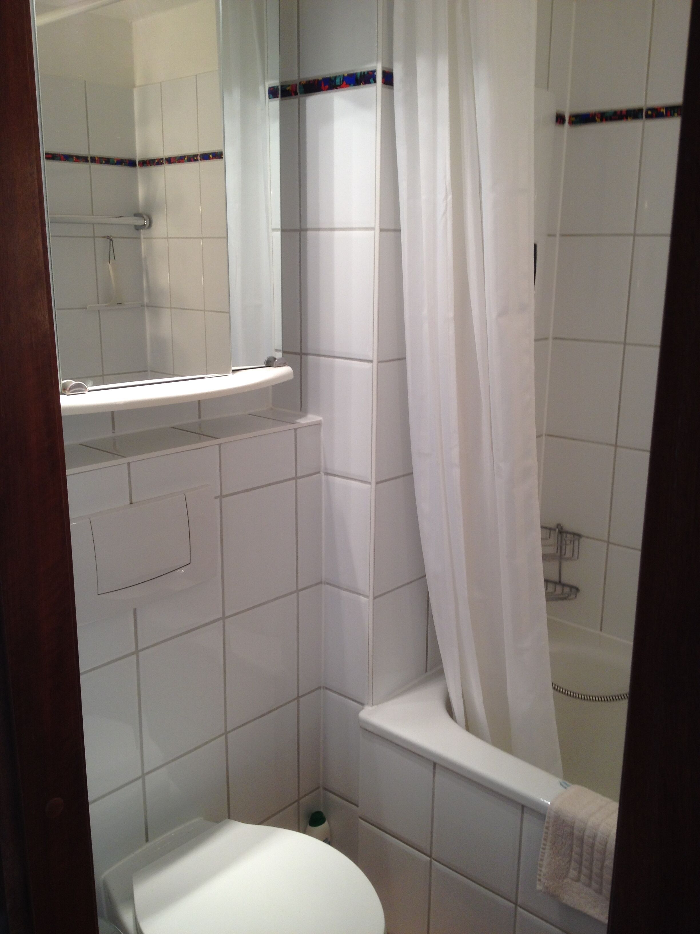 A small, tiled bathroom with a toilet, a shower, and a bathtub.