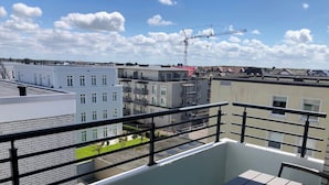 A rooftop terrace with a pool, a table, and a view of surrounding buildings.