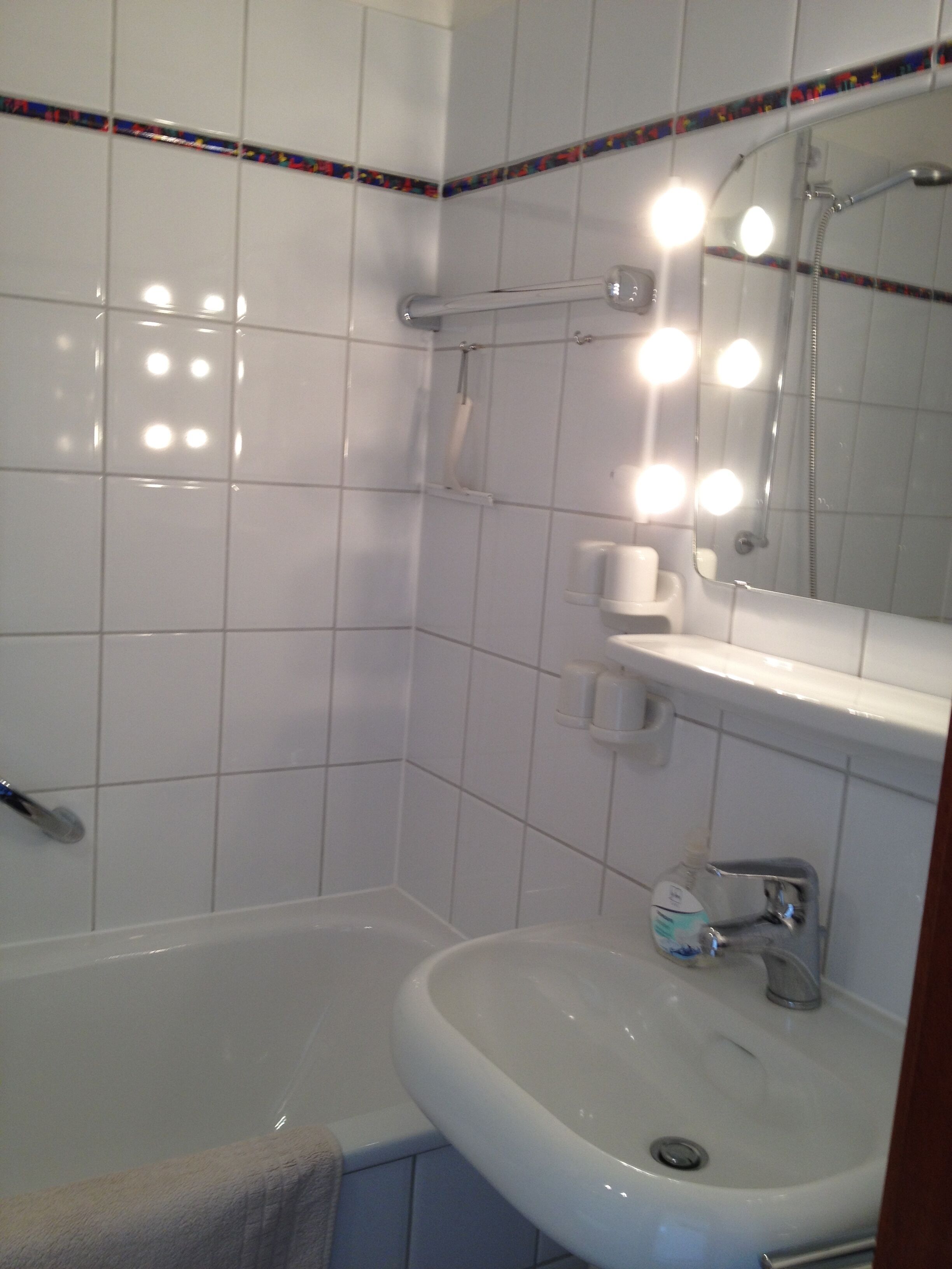 A bathroom with a bathtub, a sink, and a mirror with lights.