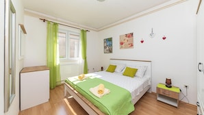 Une chambre à coucher avec un lit, une table de chevet, une lampe et une fenêtre avec des rideaux.