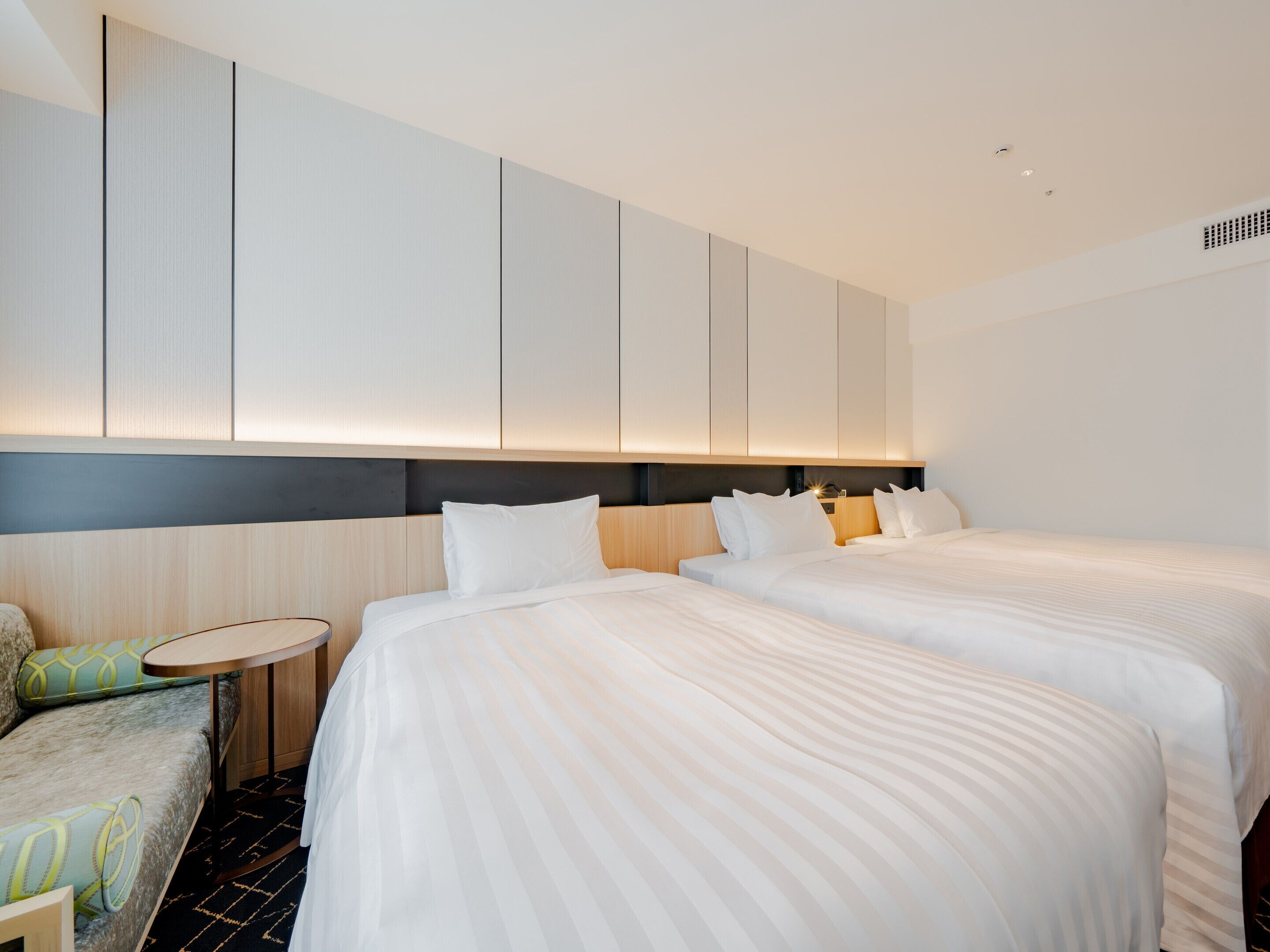A hotel room with two beds, a small round table, and a sofa.