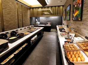 A buffet setup with various food items and a chef in the background.