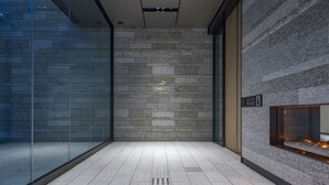 A modern interior with a stone wall, a glass partition, and a fireplace. - KEIO PRELIA HOTEL SAPPORO (Sapporo)