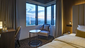 A hotel room with a large window, a bed, a chair, a small table, and a desk. - KEIO PRELIA HOTEL SAPPORO (Sapporo)