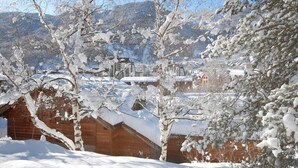 Ein verschneites Dorf mit Holzhäusern und schneebedeckten Bäumen.