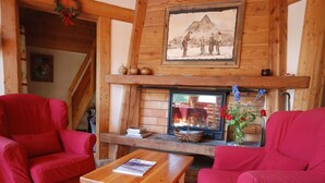 Ein gemütliches Wohnzimmer mit Kamin, Holzmöbeln und einem Gemälde darüber.