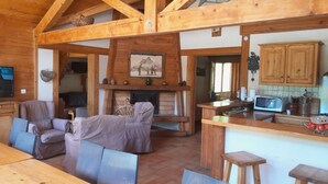 Ein rustikaler Holzinnenraum mit Essbereich, Sofas, Kamin und Küchenzeile mit Holzschränken und Mikrowelle.