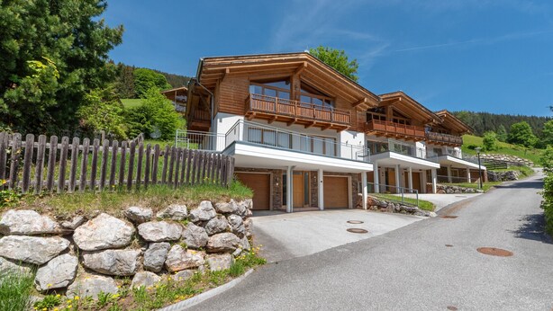 A modern wooden house with a stone wall, a wooden fence, and a clear sky. - Ski Chalet Jim / 300 m from ski lift (Zell am See)