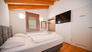 Ett sovrum med en säng, en tv, en spegel, ett fönster med persienner och en skylt med texten ”Privat” på dörren.