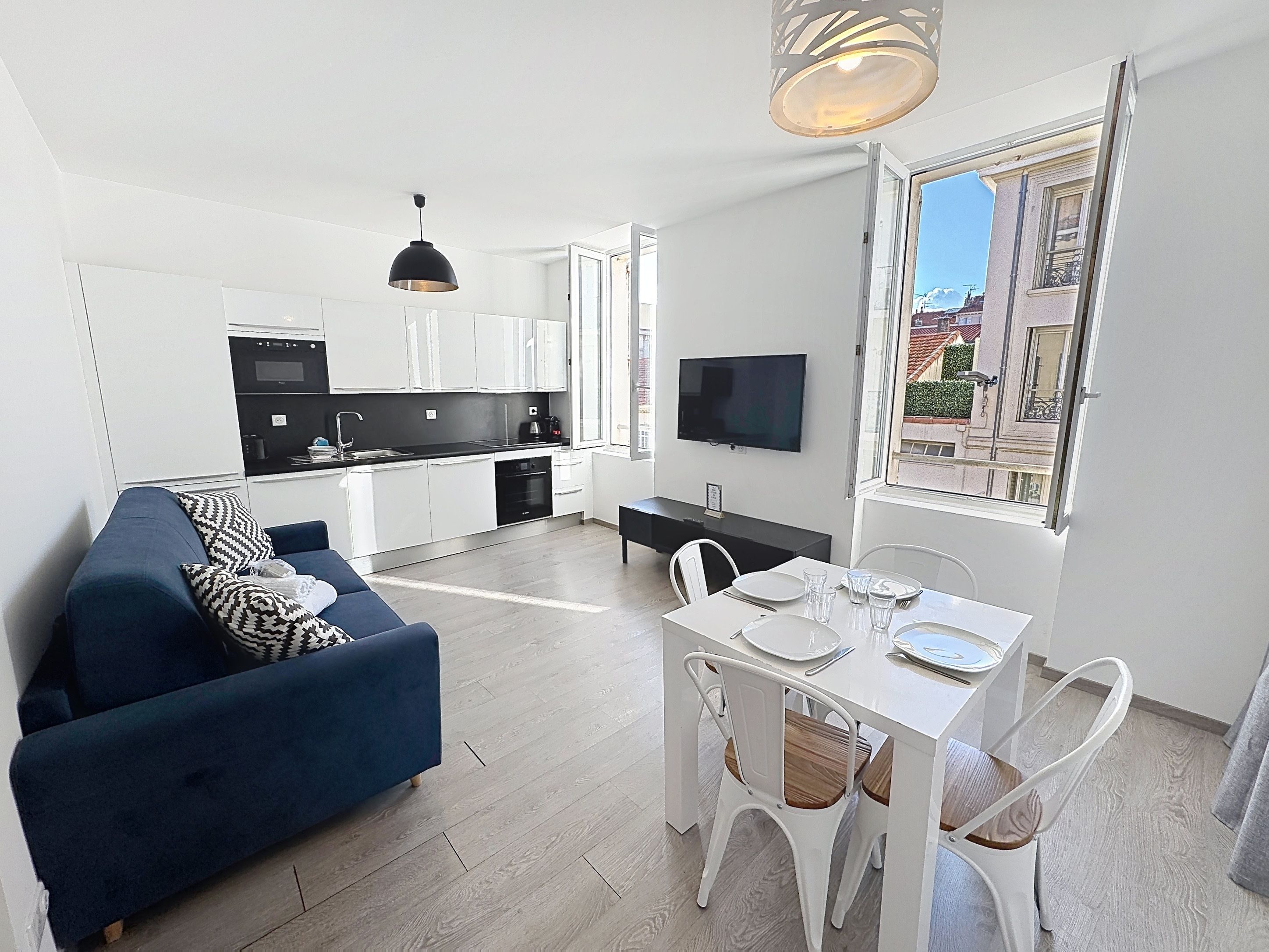Un apartamento moderno con sala de estar, comedor, cocina y un televisor montado en la pared.
