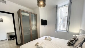 A hotel room with a bed, a desk, a chair, a wardrobe, a TV, and a window. - Cosy 1-BR fully renovated - heart of Cannes, Croisette 1 mn Olam Properties (Cannes)