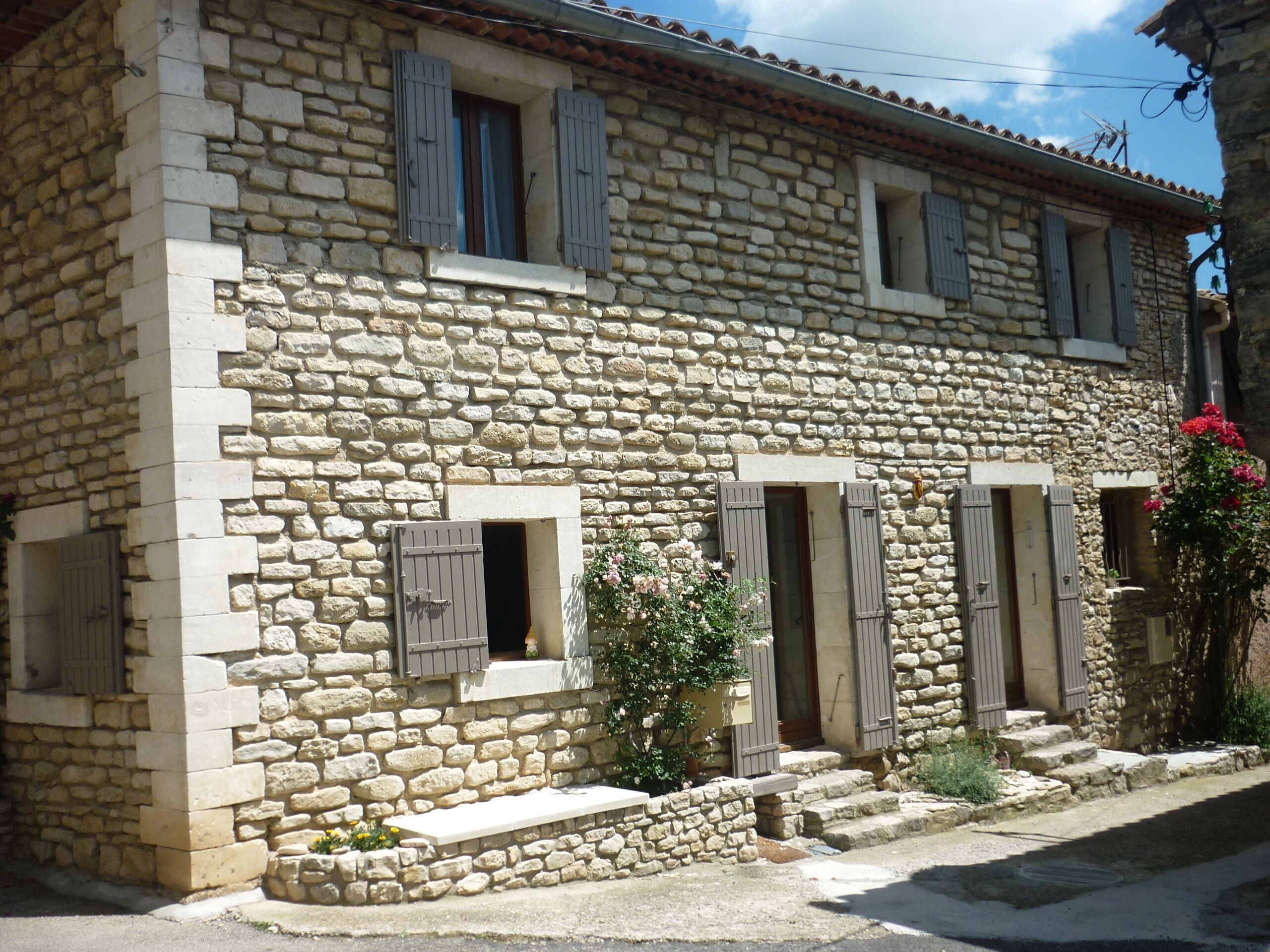 A stone building with multiple windows and doors, featuring a rustic architectural style.