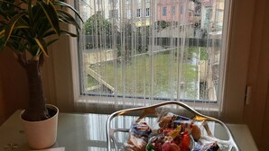 A window with a view of buildings, a potted plant, and a basket of snacks on a table. - Cannes, 2 rooms Furnished 3 stars 10 mn from the Palais and the beach (Cannes)