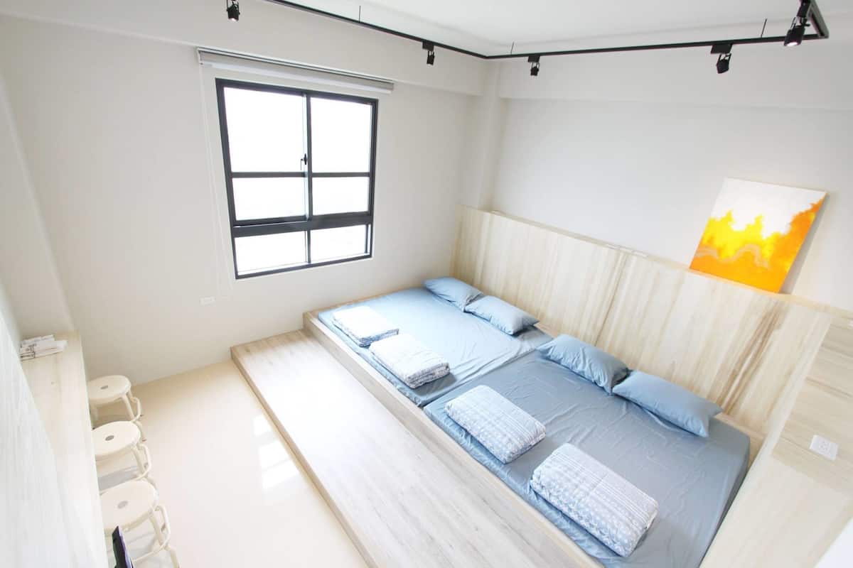 A bedroom with a large bed, a window, and a painting on the wall.