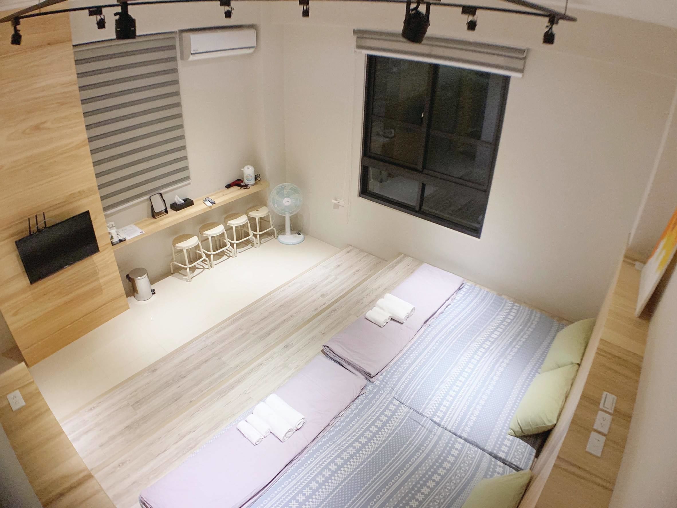 Une chambre moderne avec un lit, un bureau, une chaise, un ventilateur et une fenêtre.