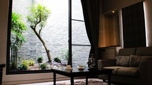 A living room with a large window, a sofa, a coffee table, and a small indoor garden. - Yin Shui Han Motel (Kaohsiung)