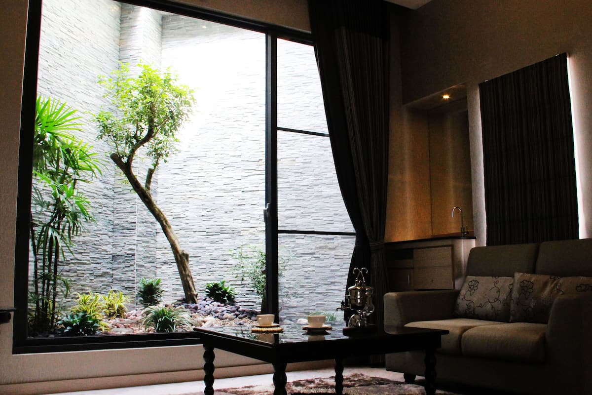 A living room with a large window, a sofa, a coffee table, and a small indoor garden.