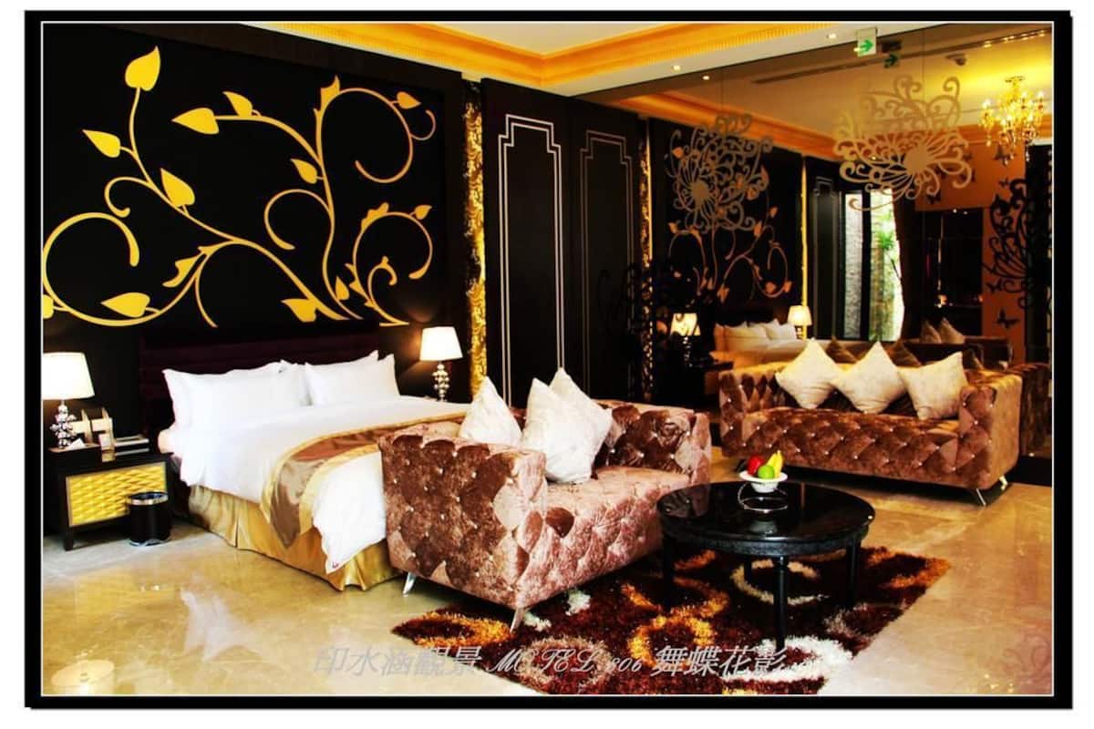 A luxurious hotel room with a large bed, a sofa, a coffee table, and decorative wall art.