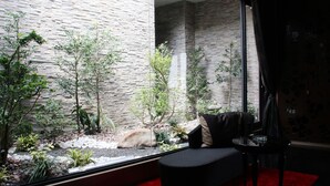 A modern interior with a stone wall, a glass enclosure with plants, and a red carpeted area. - Yin Shui Han Motel (Kaohsiung)
