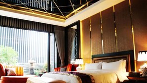 A modern hotel room with a large bed, a sofa, and a view of greenery outside. - Yin Shui Han Motel (Kaohsiung)