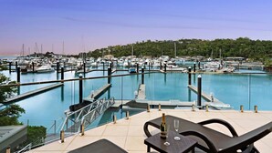 Un puerto deportivo con barcos amarrados, una piscina y zona de estar al aire libre con una botella de champán.