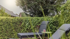 Un jardín con zona de estar que incluye dos sillones reclinables y una mesita con una taza.