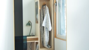 Ein Schlafzimmer mit einem Bett, einem Kleiderschrank, einem Schreibtisch und einem Spiegel.