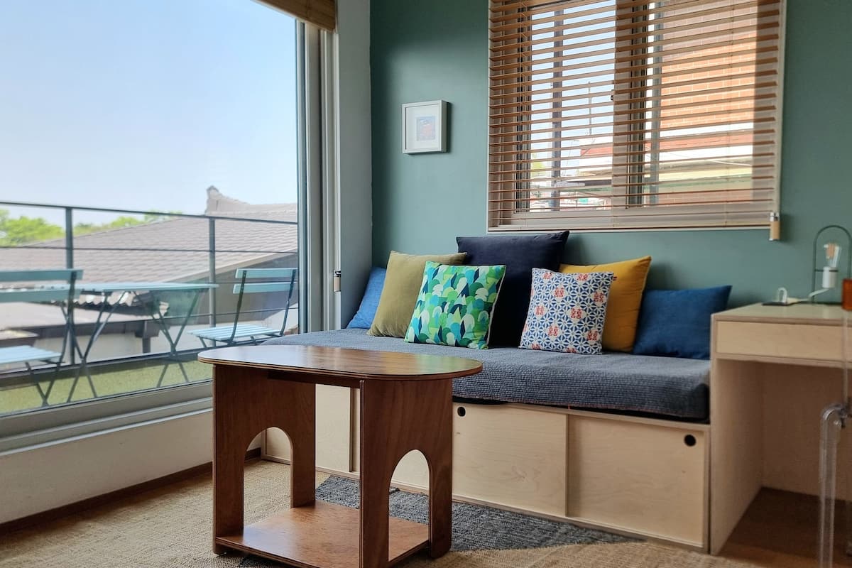 A cozy room with a sofa, a small wooden table, and a desk.