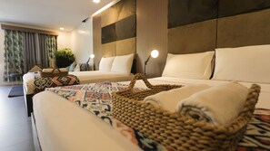A modern hotel room with a large bed, a smaller sofa, and a desk. There are two bedside lamps and a plant in the corner. - Treetop Suites (Coron)
