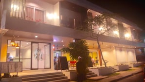 A modern hotel with a glass facade, outdoor seating area, and a sign reading "REETOP". - Treetop Suites (Coron)