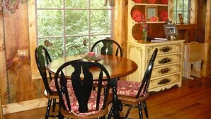 Un comedor con mesa y sillas de madera, una lámpara de araña y un aparador con objetos decorativos.