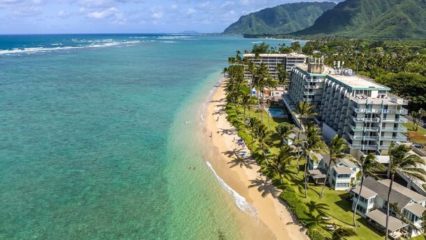 Oversigtsbillede af et strandhotel med pool, strand og bjerge i baggrunden.