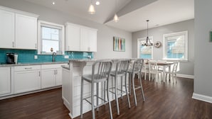 Une cuisine moderne avec des meubles blancs, un coin bar et un espace repas.