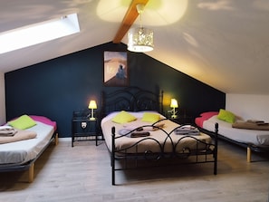 Ein gemütliches Schlafzimmer im Dachgeschoss mit schrägen Wänden, einem großen Bett mit Kopfteil, zwei Nachttischen mit Lampen und einem Bild an der Wand.