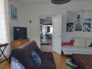 A living room with a television, a sofa, a coffee table, and a dining area in the background.