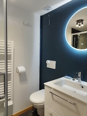 Ein Badezimmer mit Toilette, Waschbecken und Spiegel sowie einem Handtuchhalter.