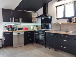 Une cuisine moderne avec des meubles de couleur noire, des appareils en acier inoxydable, un lave-vaisselle, une cuisinière et un évier.