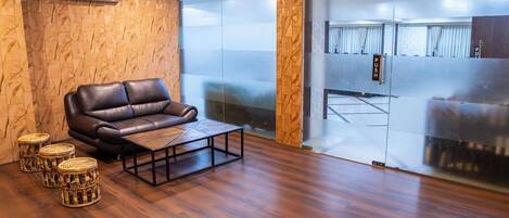 A modern living room with a leather sofa, a wooden coffee table, and three wicker side tables.
