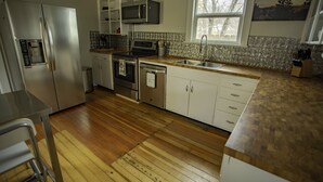 Una cocina moderna con electrodomésticos de acero inoxidable, suelo de madera y un ventanal que proporciona luz natural.
