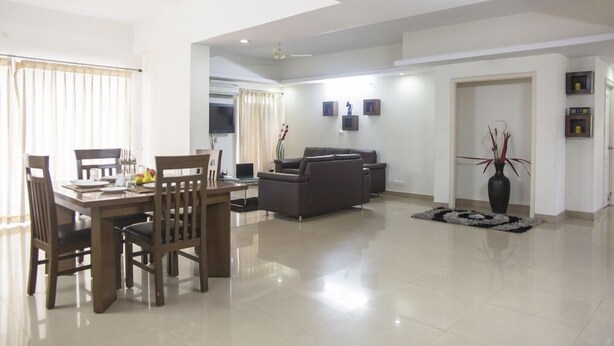 A spacious living room with a dining area, a sofa set, and a TV. - SKYLA Serviced Apartments Banjara Hills (Hyderabad)