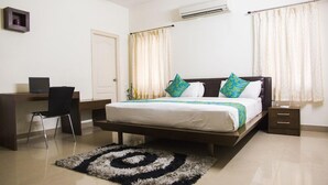 A bedroom with a bed, a desk, a chair, and a small bedside table. - SKYLA Serviced Apartments Banjara Hills (Hyderabad)
