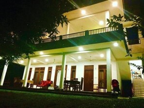 A two-story building with a balcony, multiple windows, and a covered outdoor seating area. - Villa wanderlust (Hikkaduwa)