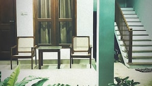 Un espacio exterior cubierto con dos sillas de madera, una mesa y una planta en maceta.