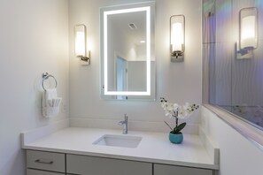 A modern bathroom with a white sink, a large mirror, and two wall-mounted lights. - 🥳​🎉  KILLER ROOFTOP LOUNGE WITH FIRE PIT & BBQ (Nashville)