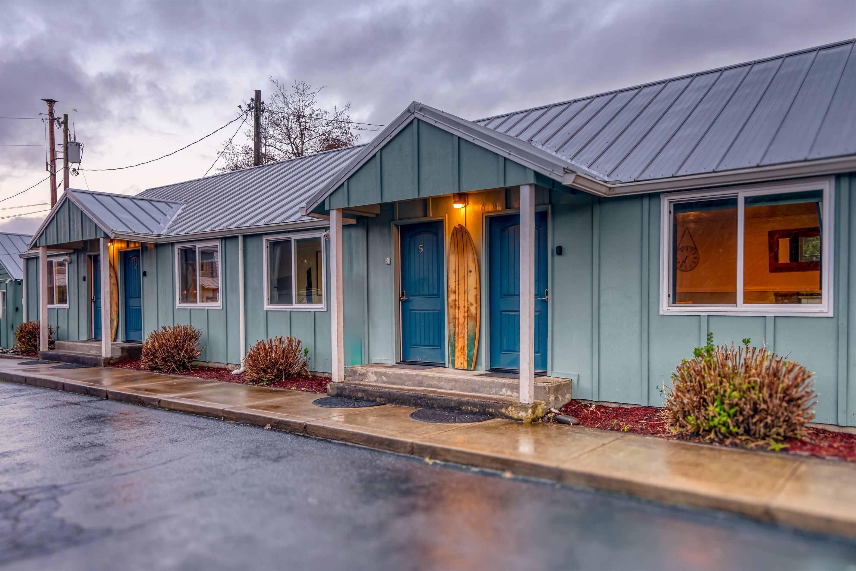 Une rangée de bâtiments de style motel, avec des portes bleues et un petit espace porche.