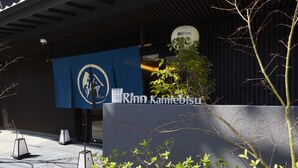 Un bâtiment sur lequel est accrochée une banderole bleue affichant le logo et le nom « Rinn Kamieblus ».