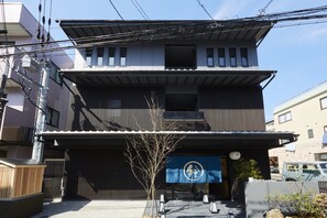 Un edificio de dos pisos con un toldo azul y un letrero que dice "Rin Kamekura".